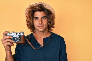 Şapkalı genç İspanyol bir adam elinde klasik bir kamera tutuyordu. Düşünce tarzı ve ayık ifadesi vardı. Kendine güveni tamdı. 