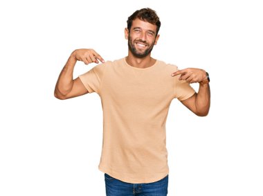 Sakallı, sıradan tişörtlü, kendine güvenen, yüzünde gülümseme olan, kendini gururlu ve mutlu gösteren yakışıklı bir genç.. 