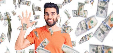 Sakallı, sıradan tişörtlü genç ve yakışıklı bir adam beş numarayı gösteriyor ve gülümsüyor. Kendinden emin ve mutlu..