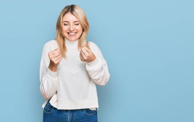 Sıradan bir kazak giyen, kolları havada, gözleri kapalı zaferi kutlayan genç, beyaz bir kadın. Kazanan konsept. 