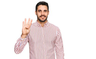 Genç İspanyol adam iş gömleği giyer ve parmaklarıyla dört numarayı gösterir ve gülümserken kendinden emin ve mutludur.. 