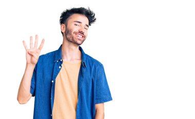 İspanyol asıllı genç adam, gündelik giysiler giyip dört numarayı gösterip işaret ederken kendinden emin ve mutlu bir şekilde gülümsüyor.. 