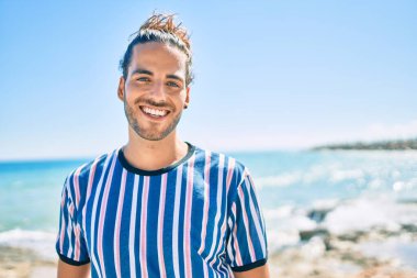 Genç İspanyol adam gülümsüyor, mutlu bir şekilde kameraya bakıyor..