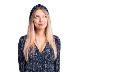 Genç, güzel, sarışın, sıradan kıyafetler giyen, gülümseyen, yan tarafa bakıp düşünen bir kadın.. 