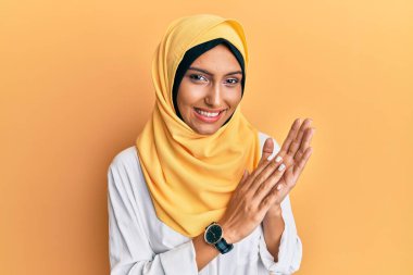 Genç esmer Arap kadın geleneksel başörtüsü takıyor. Alkışlıyor ve alkışlıyor. Mutlu ve neşeli. 