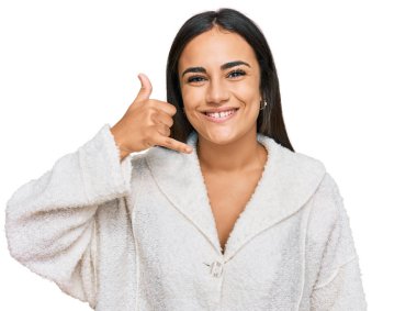 Genç esmer kadın günlük kıyafetler giyip gülümsüyor telefonla el ve parmaklarıyla jest yapıyor telefonda konuşuyor gibi. iletişim kavramları. 