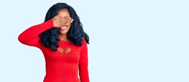 Güzel afro-amerikan kadın günlük kıyafetler giyiyor gülümsüyor ve elleri yüzüne gülüyor şaşırtmak için gözleri örtüyor. kör kavram. 