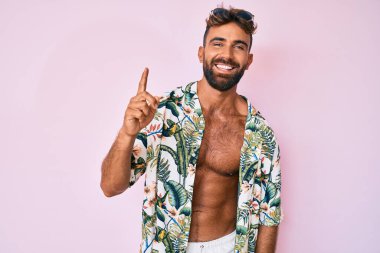 Yaz kıyafetleri giymiş genç İspanyol adam gülümsüyor mutlu bir şekilde elini ve parmağını yana doğru gösteriyor. 