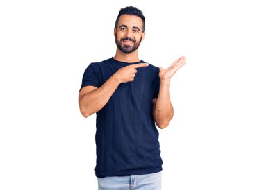 Gündelik kıyafetler giyen genç İspanyol adam kameraya hayret ediyor ve gülümsüyor.. 