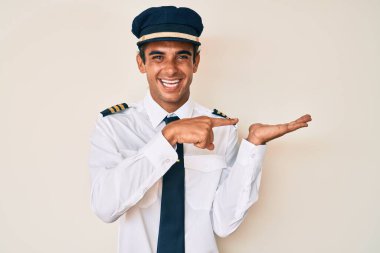 Uçak pilotu üniforması giyen genç İspanyol adam kameraya hayret ediyor ve gülümsüyor.. 