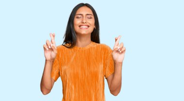 Genç esmer Arap kadın, günlük kıyafetler giyip umut ve gözlerin kapalı gülümseyerek el sallıyor. Şans ve batıl inançlar. 