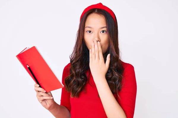 Menina Chinesa Bonita Jovem Segurando Livro Cobrindo Boca Com Mão — Fotografia de Stock