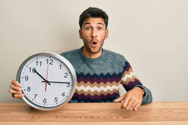 Joven Hombre Guapo Sosteniendo Gran Reloj Asustado Sorprendido Con Boca — Foto de Stock