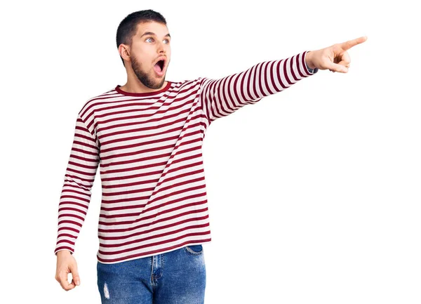 Young Handsome Man Wearing Striped Sweater Pointing Finger Surprised Ahead — Stock Photo, Image