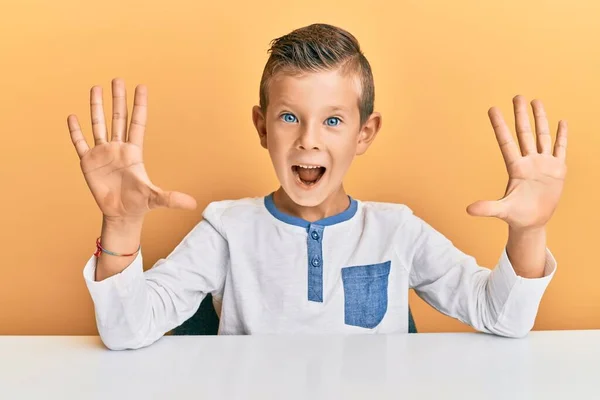 Schattig Blank Kind Draagt Casual Kleding Zittend Tafel Tonen Wijzen — Stockfoto