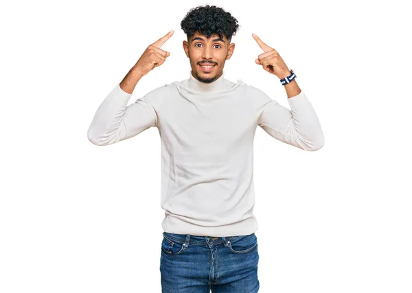 若いアラブ人男性を着てカジュアルな冬のセーター両手の指で頭を指して笑顔 素晴らしいアイデアや考え 良い記憶 — ストック写真