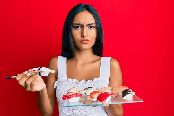 Young Brunette Woman Eating Butterfish Sushi Using Chopsticks Skeptic Nervous — Stock Photo, Image