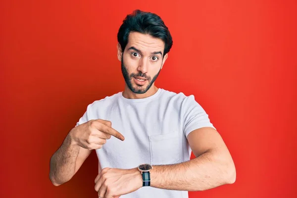 Joven Hispano Vistiendo Camiseta Blanca Casual Con Prisa Apuntando Ver — Foto de Stock