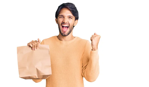 Hombre Hispano Guapo Sosteniendo Llevar Bolsa Papel Gritando Orgulloso Celebrando —  Fotos de Stock