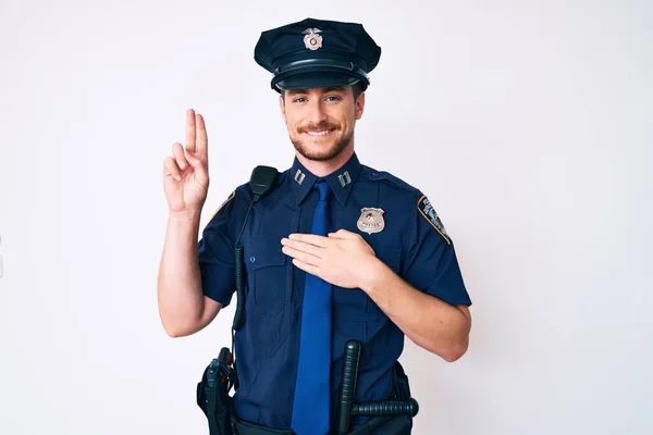 Young caucasian man wearing police uniform smiling swearing with hand on chest and fingers up, making a loyalty promise oath