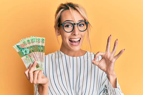 Beautiful Blonde Woman Holding Hong Kong Dollars Banknotes Doing Sign — Stock Photo, Image