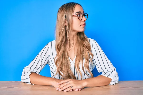 Joven Hermosa Mujer Rubia Con Gafas Sentadas Mesa Mirando Lado —  Fotos de Stock