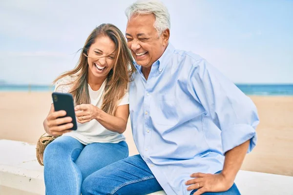 Medelålders Latinamerikanska Par Använder Smartphone Sitter Bänken Stranden — Stockfoto