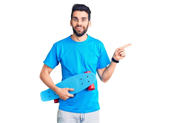 Joven Hombre Guapo Con Barba Sosteniendo Patín Sonriendo Feliz Señalando — Foto de Stock