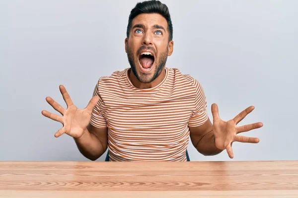 Bonito Hispânico Vestindo Roupas Casuais Sentado Mesa Louco Louco Gritando — Fotografia de Stock