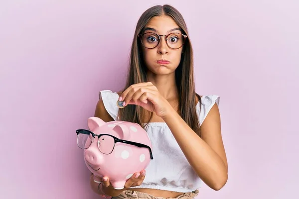 Young Hispanic Woman Holding Piggy Bank Glasses Coin Puffing Cheeks — Stockfoto