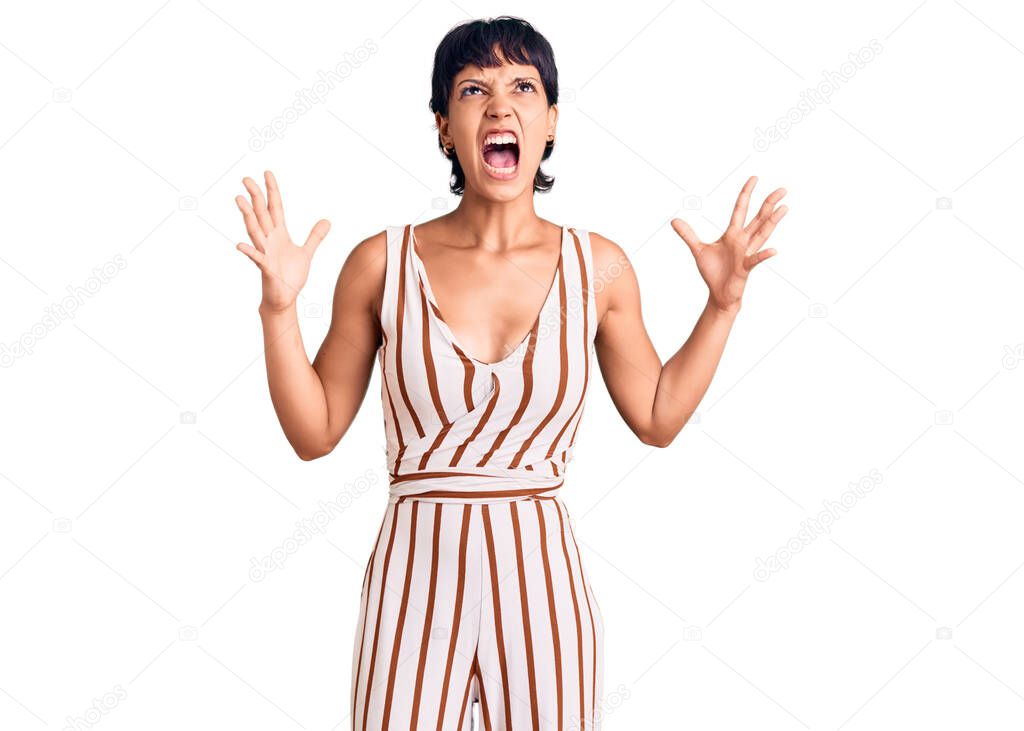 Young brunette woman with short hair wearing summer outfit crazy and mad shouting and yelling with aggressive expression and arms raised. frustration concept. 