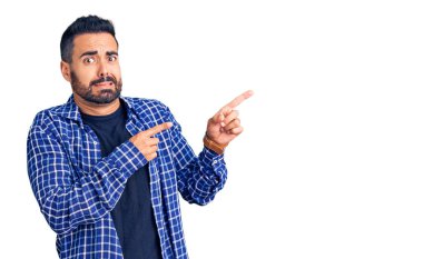 Gündelik kıyafetler giyen genç İspanyol bir adam iki eliyle endişeli ve endişeli bir ifadeye işaret ediyor. 