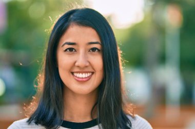 Genç İspanyol kadın gülümseyerek parkta mutlu bir şekilde yürüyor.