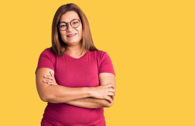 Orta yaşlı, güzel bir kadın, sıradan kıyafetler giyip kollarını çenesinde kavuşturarak yan yana bakıyor. pozitif kişi.