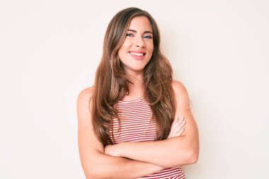 Gündelik kıyafetler giyen, kollarını kavuşturup kameraya gülümseyen güzel beyaz bir kadın. pozitif kişi. 