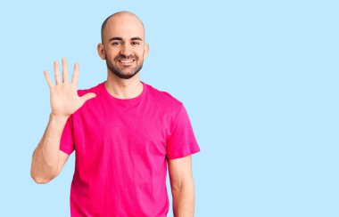 Gündelik tişört giyen genç ve yakışıklı bir adam gülümserken 5 numarayı gösteriyor ve işaret ediyor.. 