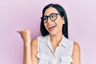 Elinde pembe kanser kurdelesi tutan genç ve güzel bir kadın kameraya hayret ediyor ve gülümsüyor.. 