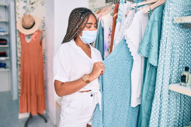 Perakende dükkanında Coronavirus güvenlik maskesi takan genç Afrikalı Amerikalı kadın.