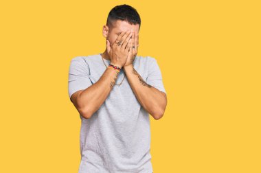 90 'ların tarzında dövmeleri olan yakışıklı bir adam. Ağlarken yüzünü ellerle kapatan üzgün bir ifade. depresyon kavramı. 