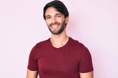 Yakışıklı, sıradan kıyafetler giyen, mutlu ve havalı bir gülümsemesi olan İspanyol bir adam. şanslı kişi. 