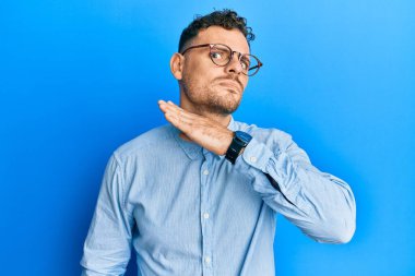 Sakallı, sıradan kıyafetler giyen ve gözlüklü, ağzı açık gülümseyen iki eli de zafer işareti yapan yakışıklı bir adam. İki numara.. 