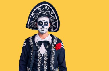 Genç adam arka planda ölü kostümü giyip komik suratlı yanakları şişiriyor. Havayla şişmiş ağız, çılgın bir ifade.. 