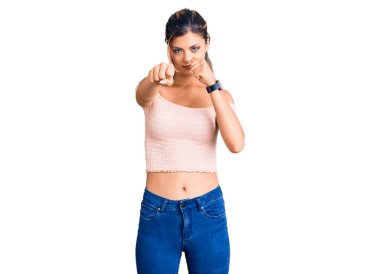 Genç, güzel bir kadın gündelik giysiler içinde dövüşmek için yumruk atıyor agresif ve öfkeli bir saldırı, tehdit ve şiddet. 