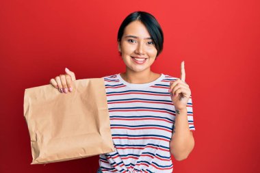 Kısa saçlı güzel genç bir kadın bir fikir ya da soruyla gülümseyen bir kesekağıdını alıp götürür. 