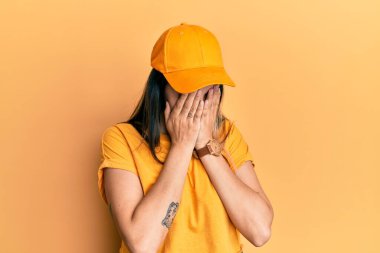 Teslimat üniforması giyen ve kep takan genç İspanyol kadın, yan tarafa bakıyor, rahat poz veriyor, kendine güvenen bir gülümsemesi var.. 