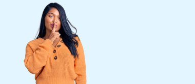 Uzun saçlı, sıradan bir kazak giyen İspanyol kadın parmakları dudaklarında sessiz olmak istiyor. sessizlik ve gizli konsept. 