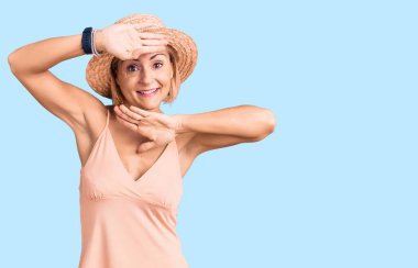 Yazlık şapkalı, neşeli gülümseyen genç sarışın kadın elleriyle dikizleme oyunu oynuyor. Şaşırdım ve çıktım. 