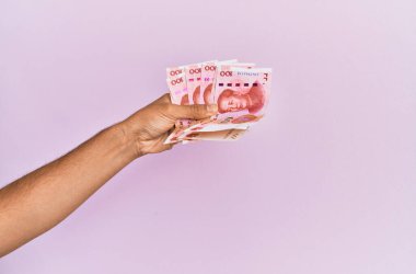 İspanyol eli 100 Yuan 'lık Çin banknotunu soyutlanmış pembe arka planda tutuyor..