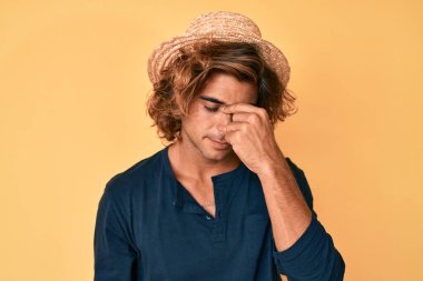 Yaz şapkası takan genç İspanyol adam yorgun burnu ve gözleri ovuşturup yorgun ve baş ağrısı çekiyor. Stres ve hüsran kavramı. 