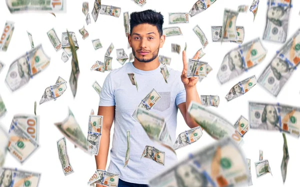 Yakışıklı Latin Amerikalı gündelik kıyafetler giyen genç adam iki numarayı gösterip işaret ederken kendinden emin ve mutlu gülümsüyor..